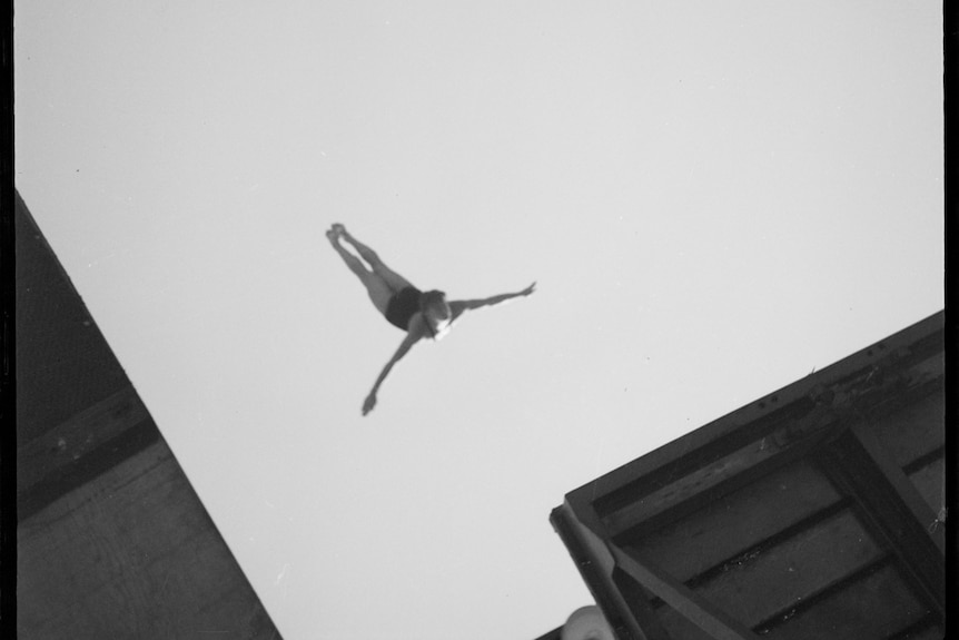 A black and white image taken from below of a person diving