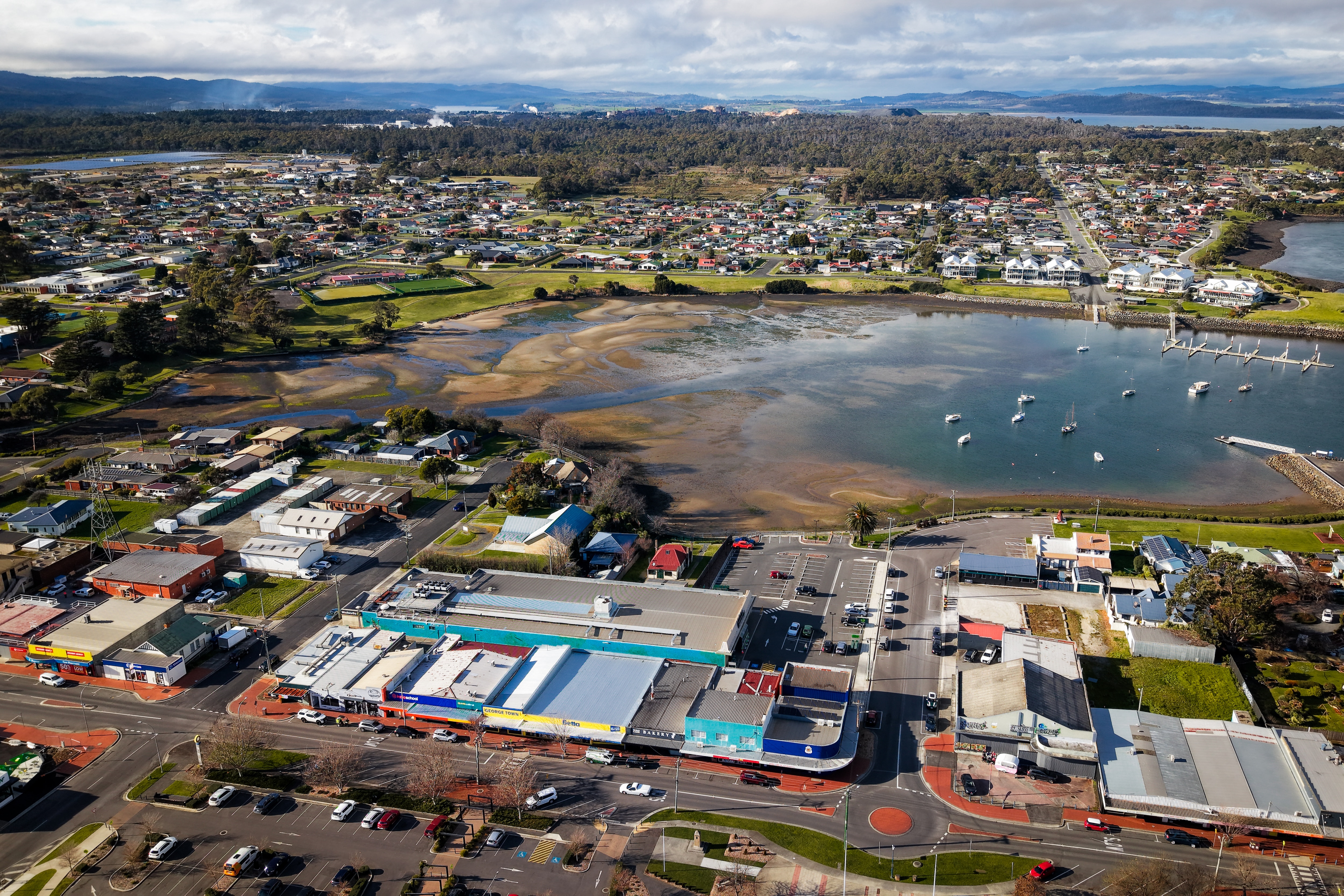 an aerial shot of a blue bay surrounded by housing and industrial buildings