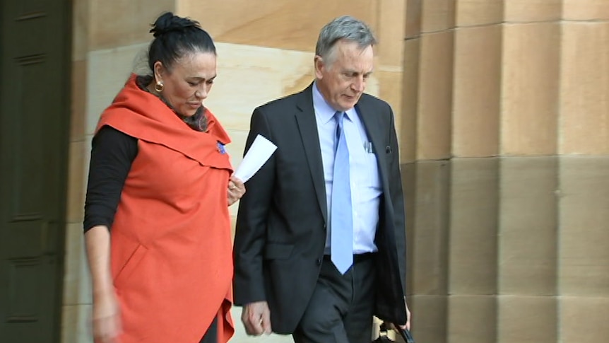 Yvonne Buza walks down stairs outside of court next to a man wearing a black suit