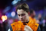F1 driver Oscar Piastri zips up his orange race suit while looking at the ground, before driving the Saudi Arabian Grand Prix
