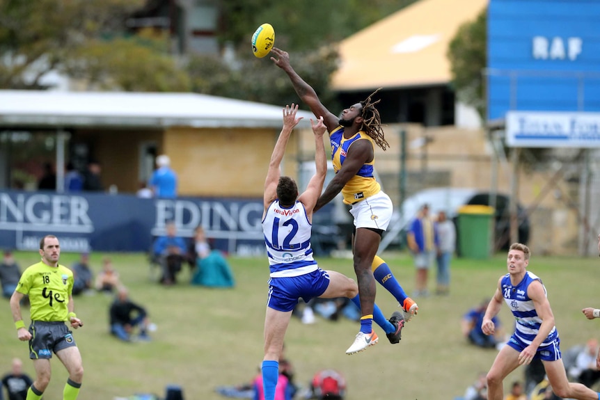 A wide shot of West Coast Eagles ruckman Nic Naitanui reaching over East Fremantle player Jon Griffin at a bouncedown.