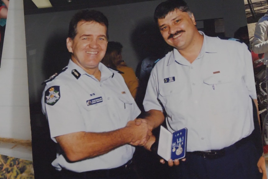 a printed-out photo of a police officer receiving a medal and shaking hands with a fellow officer