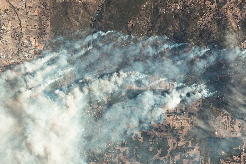 A satellite image of a massive bushfire showing smoke billowing across the land.