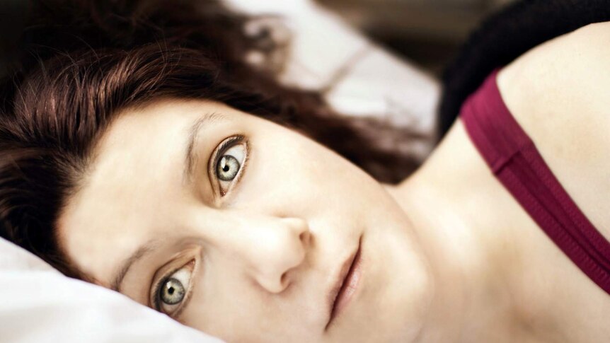 Woman lying down staring straight into camera.