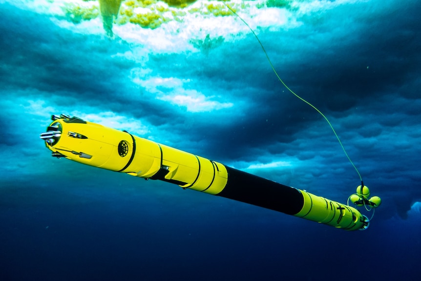 A long, yellow underwater camera in water beneath ice.