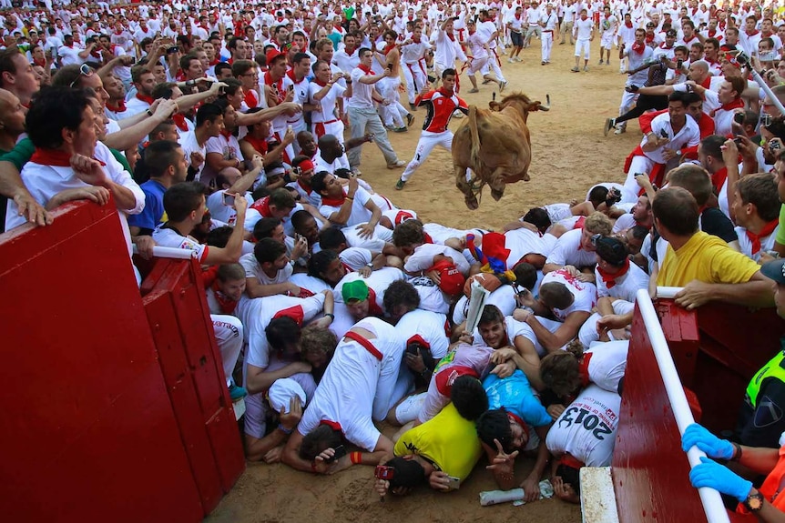 A fighting bull jumps over revellers during the running of the bulls