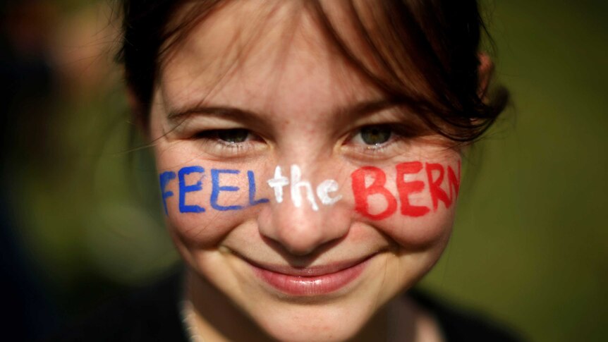 A young girl with Feel The Bern written on her face