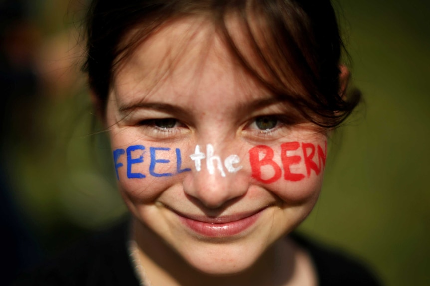 A young girl with Feel The Bern written on her face