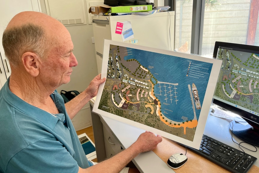 A man sitting a desk shows a concept of a marina, accommodation and jetty development