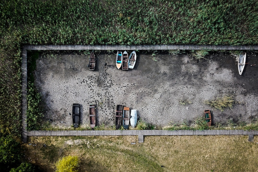 An aerial shot shows boats laying in a small port in a dried lake bed.