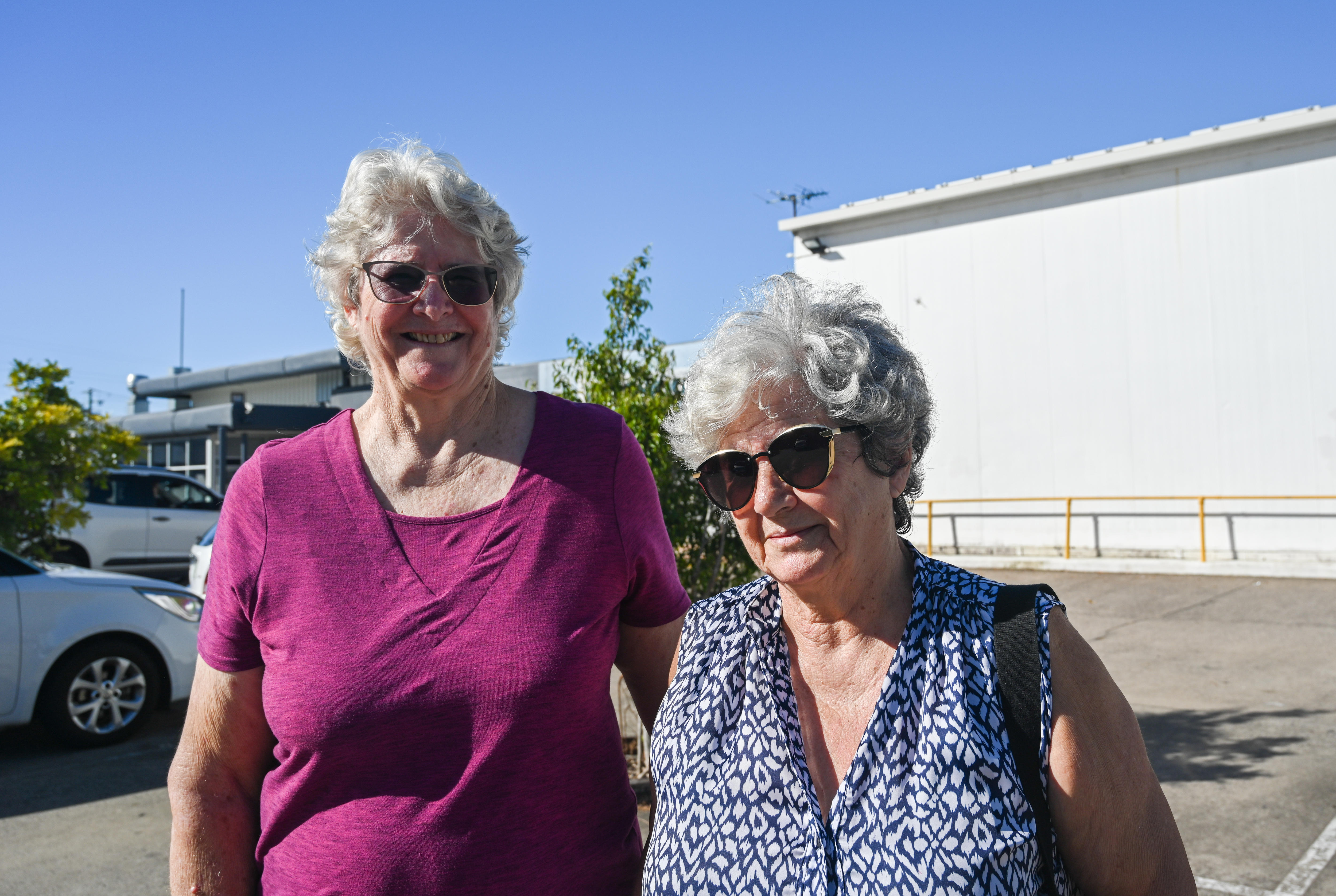 Two women standing in a car park.