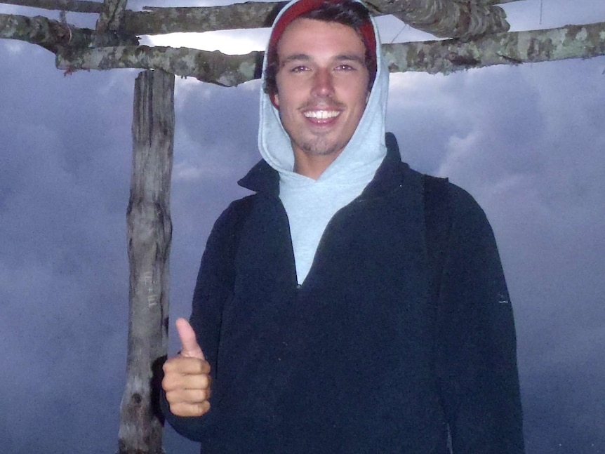 A smiling Jarrod Hampton poses for a photo with one of his thumbs up wearing a hoody outdoors.
