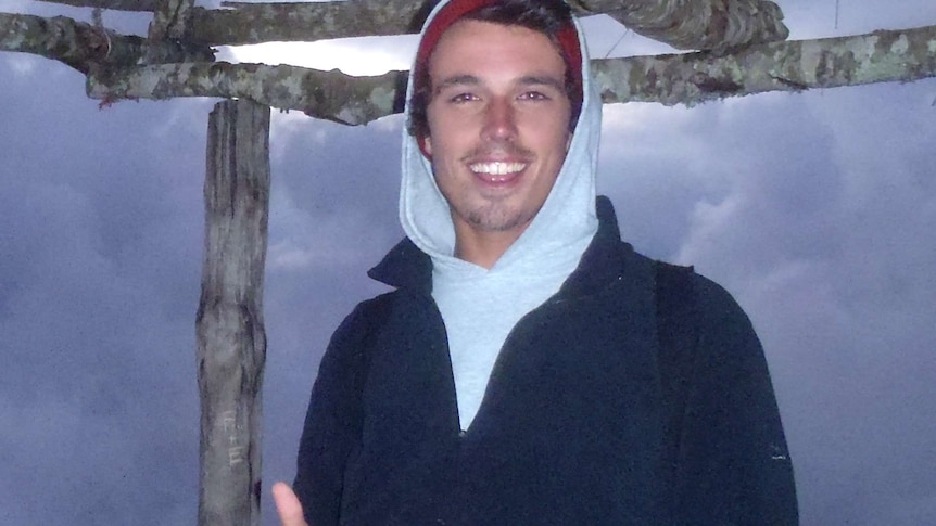A smiling Jarrod Hampton poses for a photo with one of his thumbs up wearing a hoody outdoors.