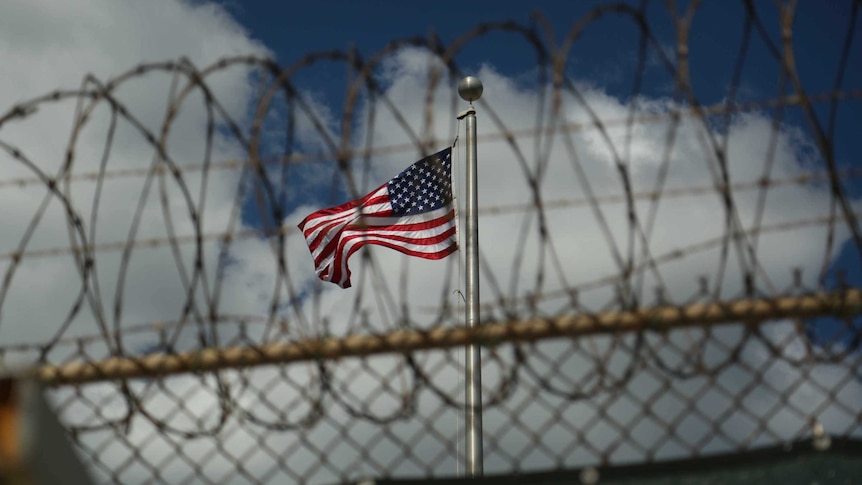 A US flag flies behind barbed wire at the Guantanamo Bay detention centre.