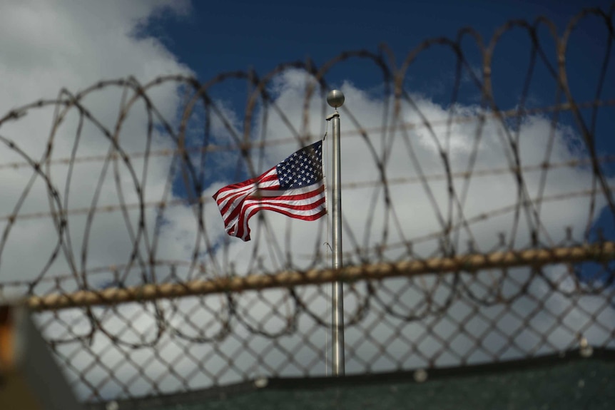 A US flag flies behind barbed wire at the Guantanamo Bay detention centre.