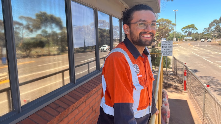 An engineer in high visibility clothing leaning on a railing. 