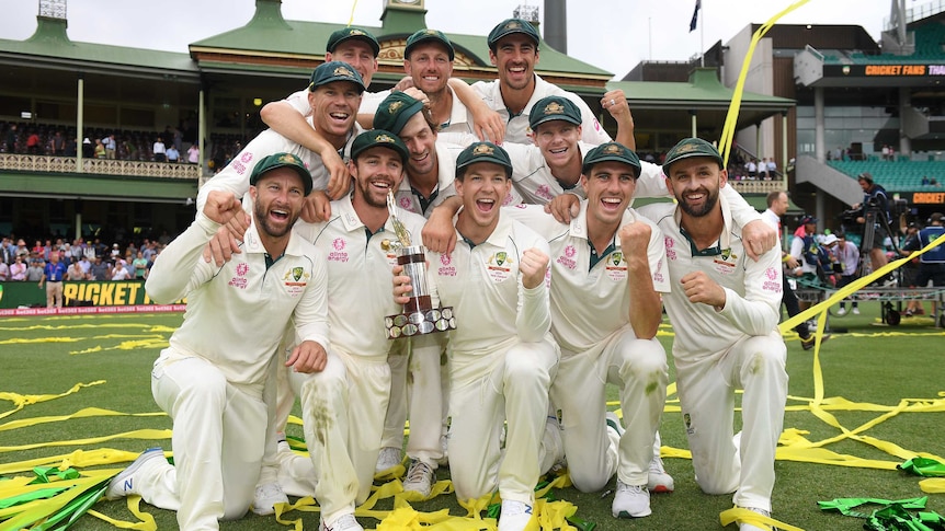 Australian cricketers pose with the Chappell Hadlee Trophy as they stand and kneel amid confetti.