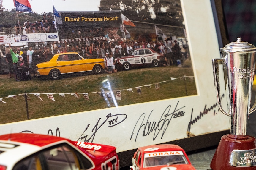Motor racing memorabilia photograph, cars and trophy.