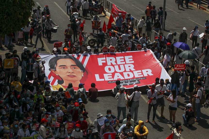 Protesters carry a banner with Aung San Suu Kyi's face reading 'free our leader'