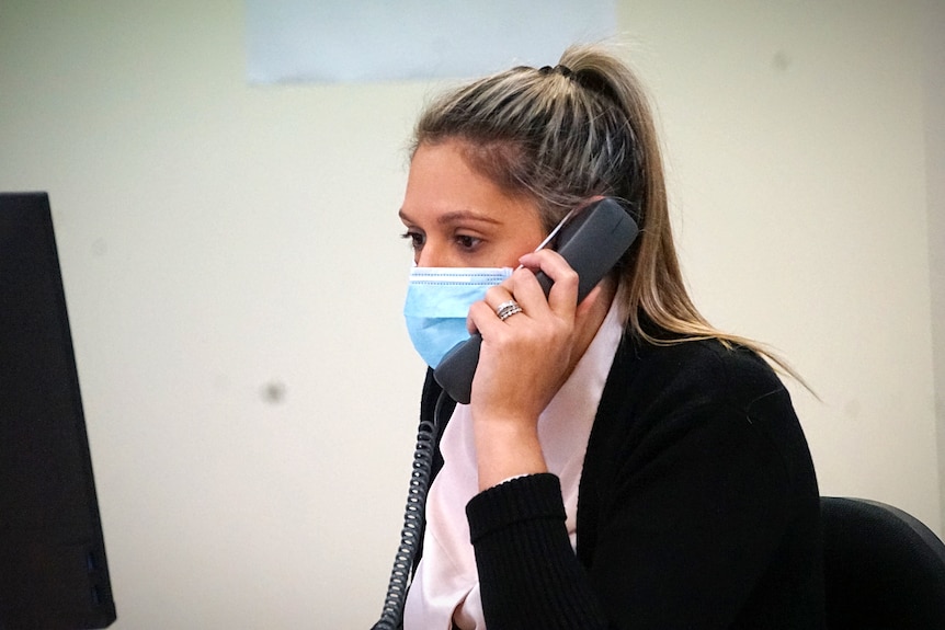 A lady sits at a phone while speaking to a close contact of a positive coronavirus case.