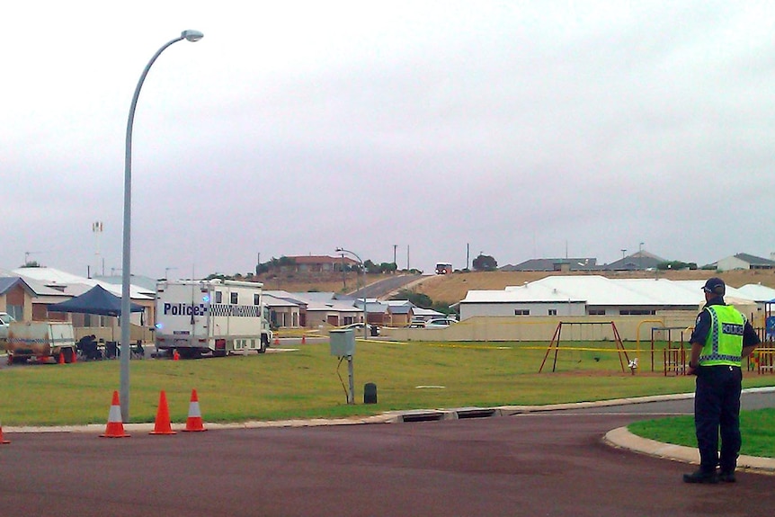 A policeman looks at a house in Port Denison, where police believe a triple murder.