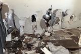 A wall is smashed with holes in the plaster 