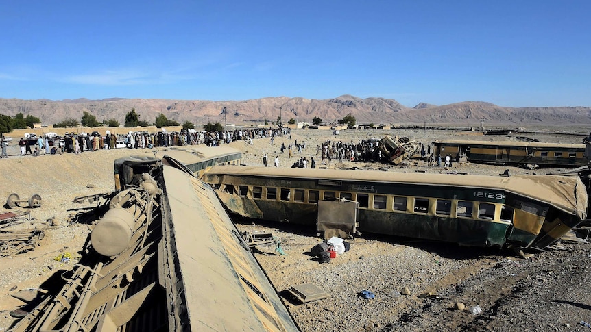 Pakistan security officials and local residents gather at the train derailment site.