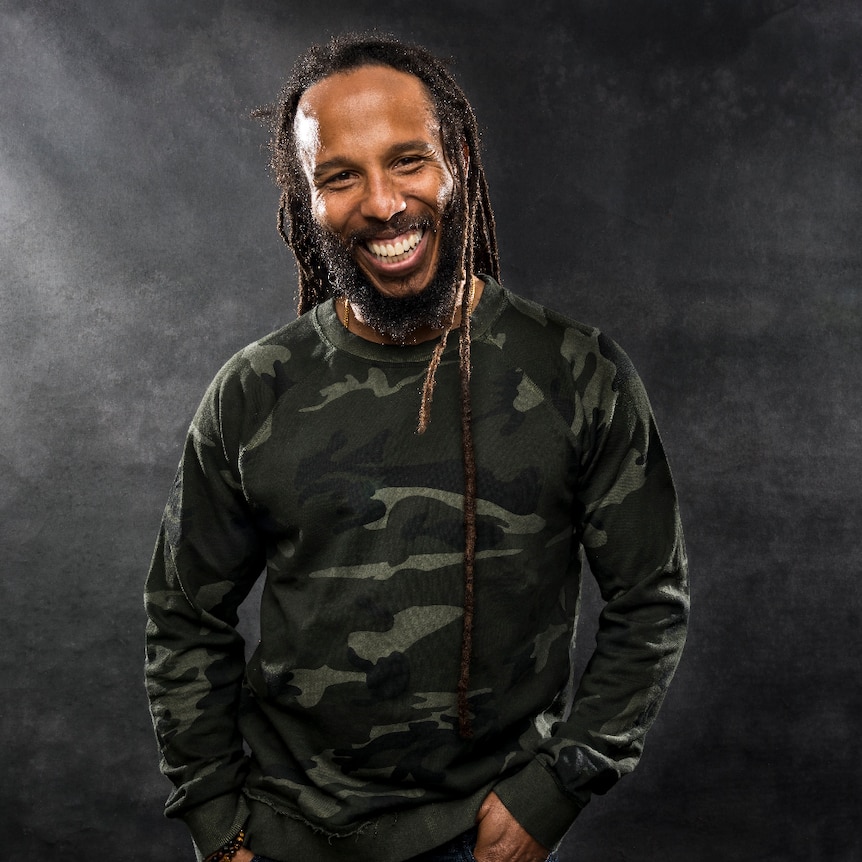 A man with dreadlocks in a camouflage jumper