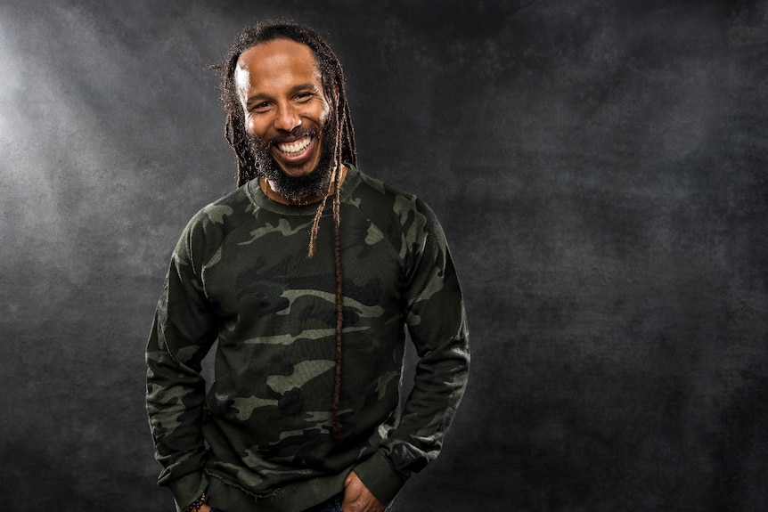 A man with dreadlocks in a camouflage jumper.