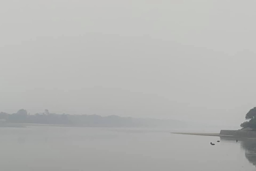 Heavy smoke has dramatically reduced visibility overlooking a body of water at Lakes Entrance.