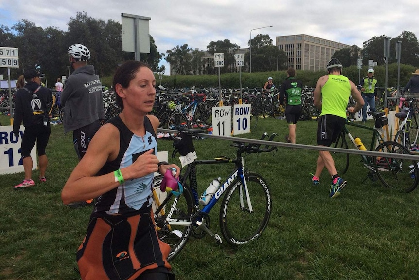 A woman runs past a row of bicycles during a triathlon