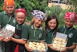 Five primary school students holding containers of baked goods.