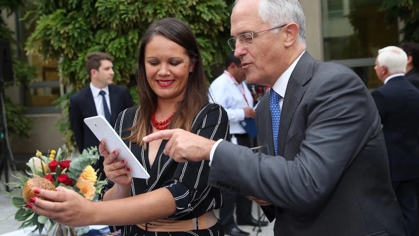 A Mikaela Jade holds at iPad that a Malcom Turnbull looks and points at.