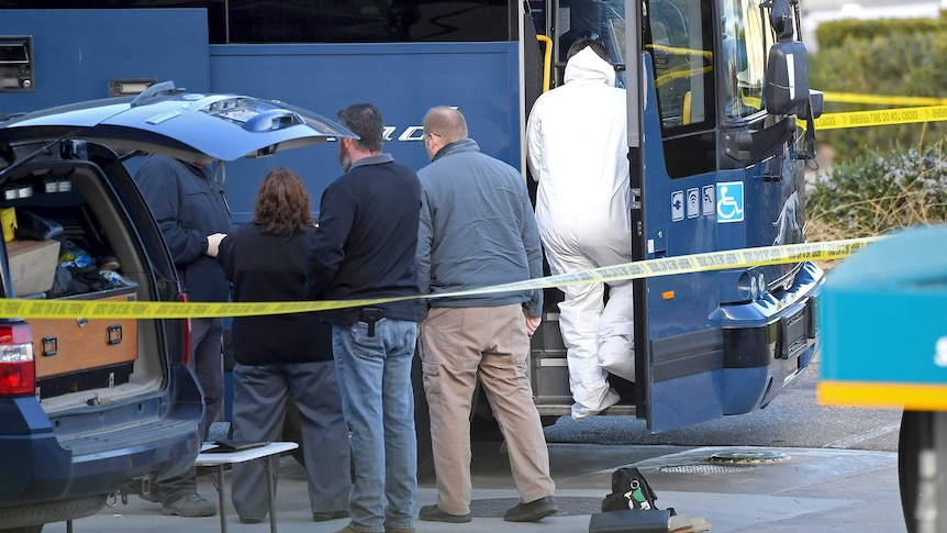 Investigators are seen outside of a Greyhound bus surrounded by yellow tape.