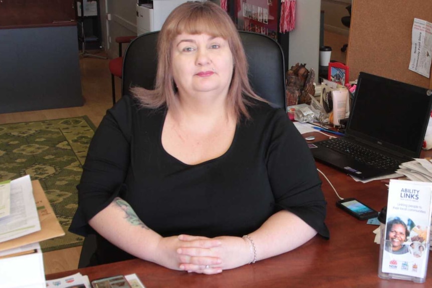 A lady sitting at a desk looking at the camera.