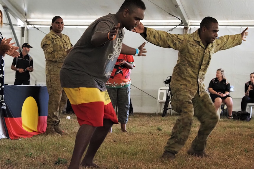 A group of Indigenous people perform a triumphant dance.