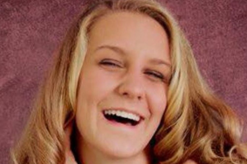 Professional portrait of smiling blonde teenager in green dress with mulberry-purple background.