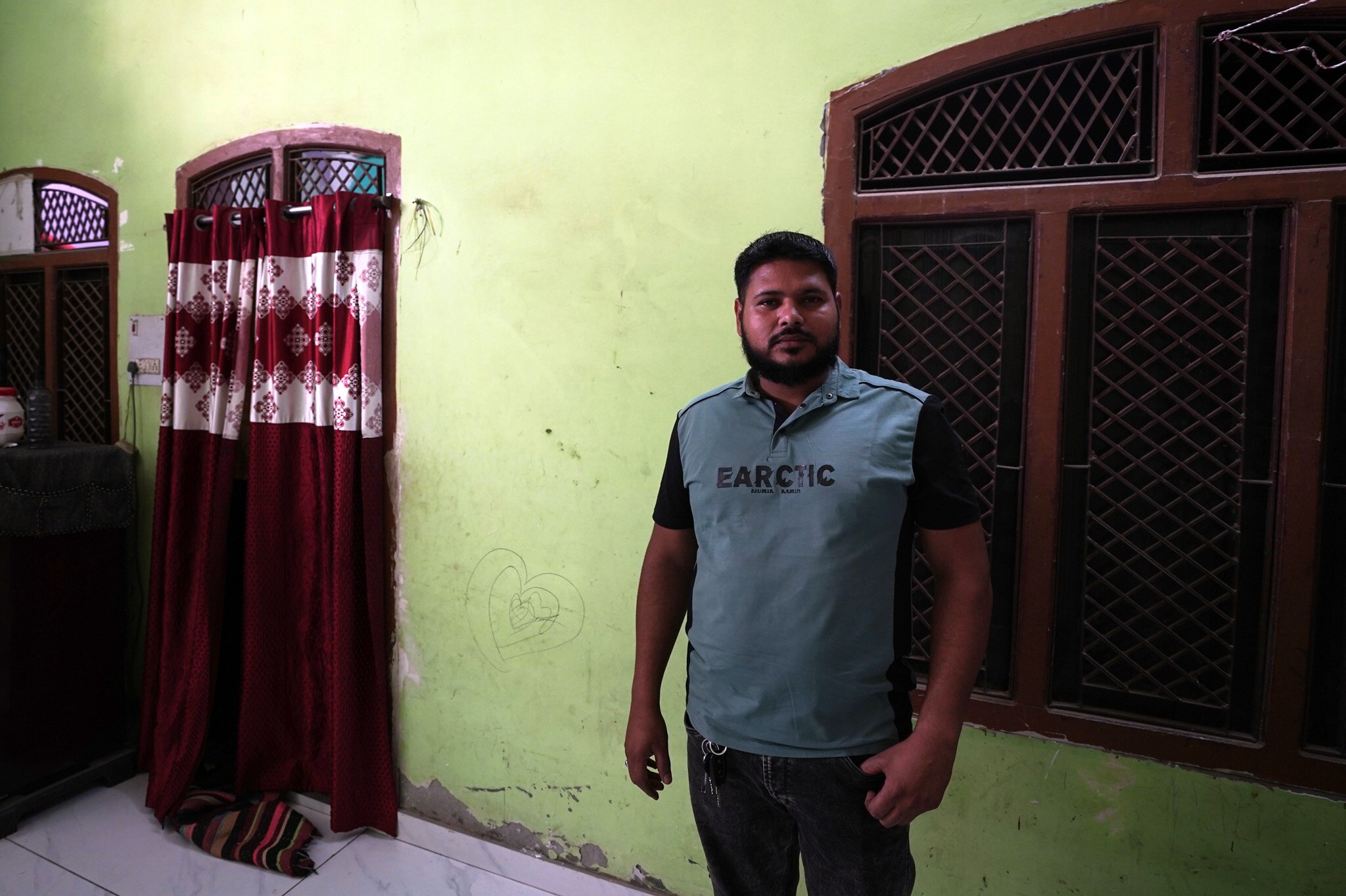 A man wearing a blue shirt stands in a room.