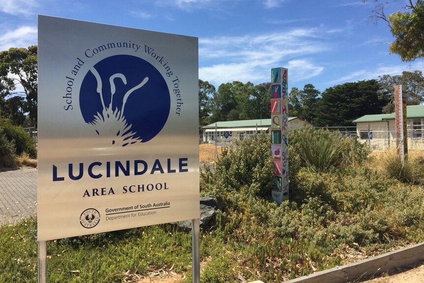 a metal sign reading "Lucindale Area School" with greenery and buildings behind