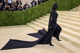 Kim Kardashian wears all black outfit including full covering face mask and cape.