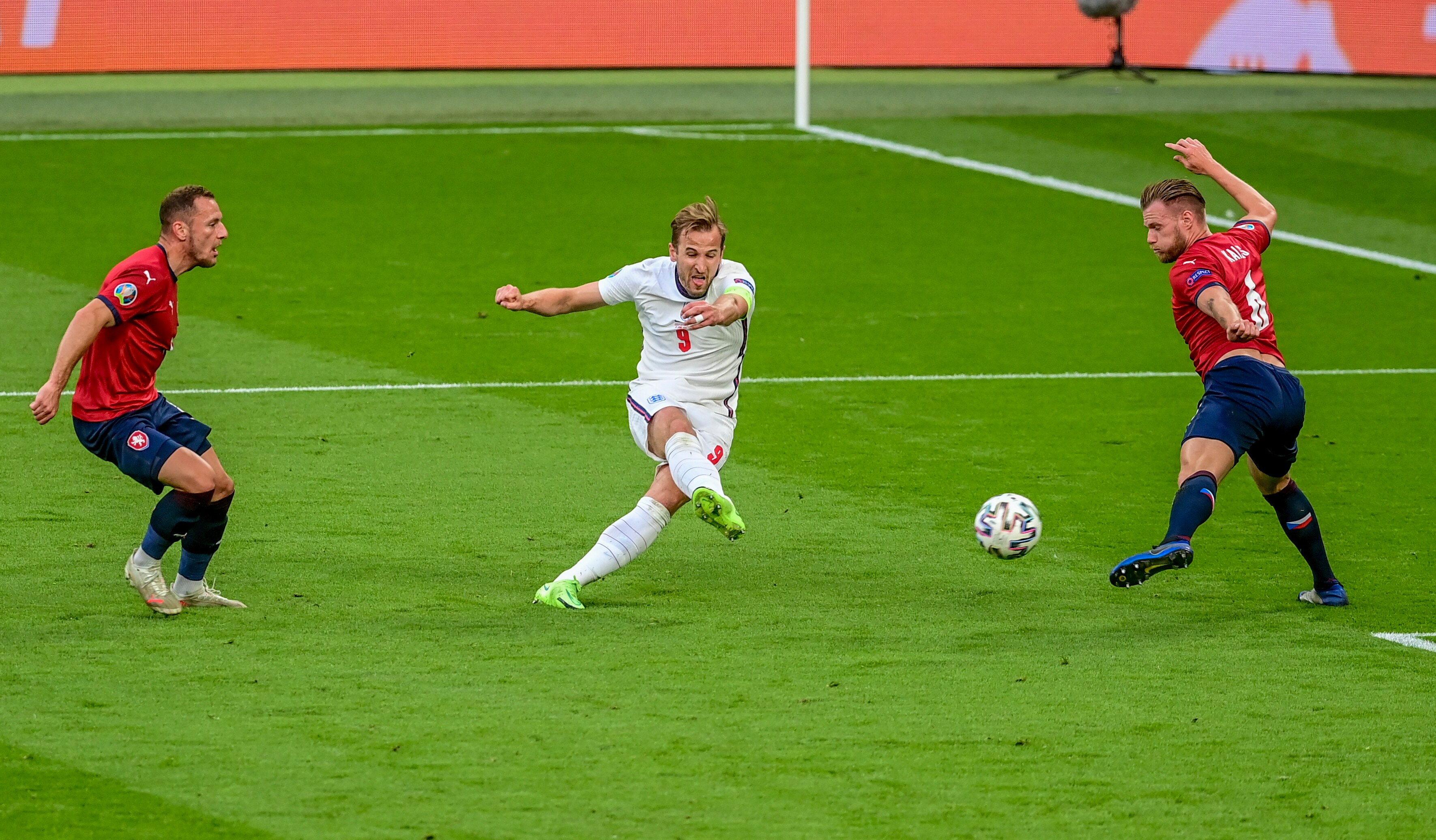 Harry Kane grimaces as he takes a shot, between two Czech defenders