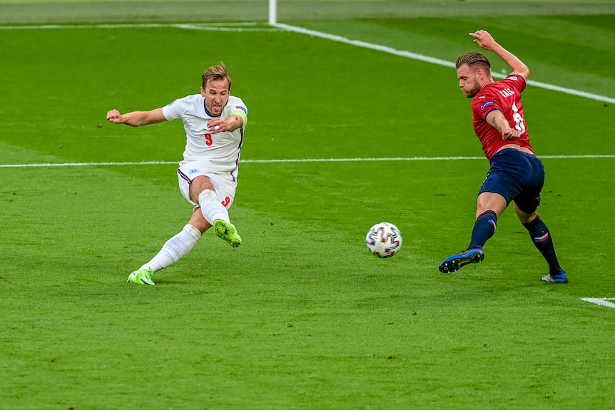 Harry Kane fa una smorfia mentre tira tra due difensori cechi