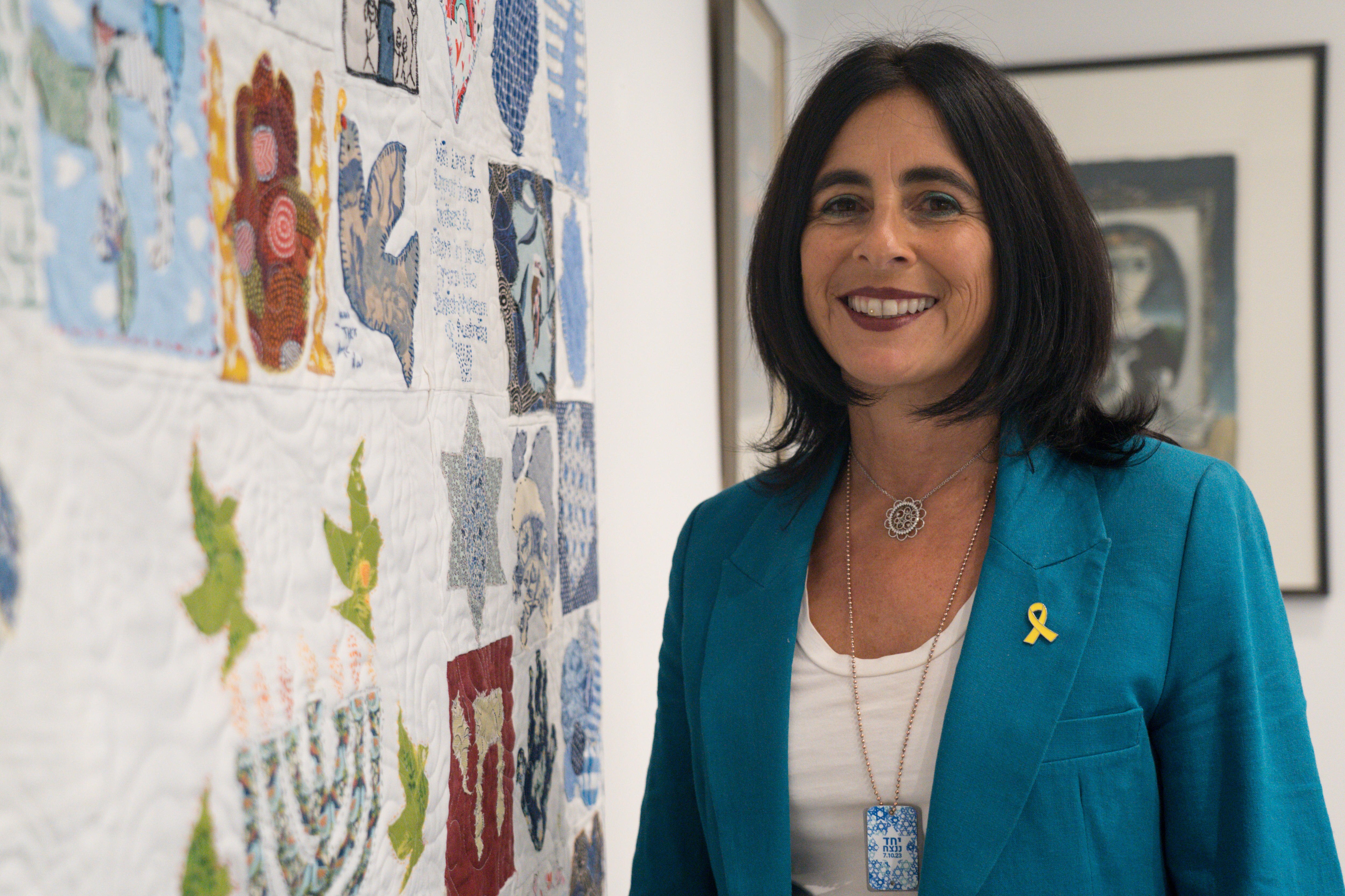 A woman in front of a quilt