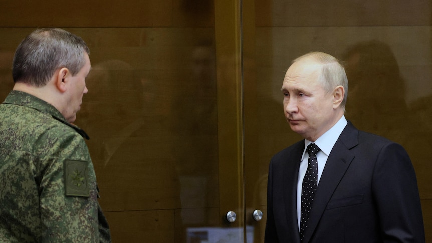 Vladimir Putin in a suit next to a man in defence uniform.