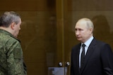 Vladimir Putin in a suit next to a man in defence uniform.