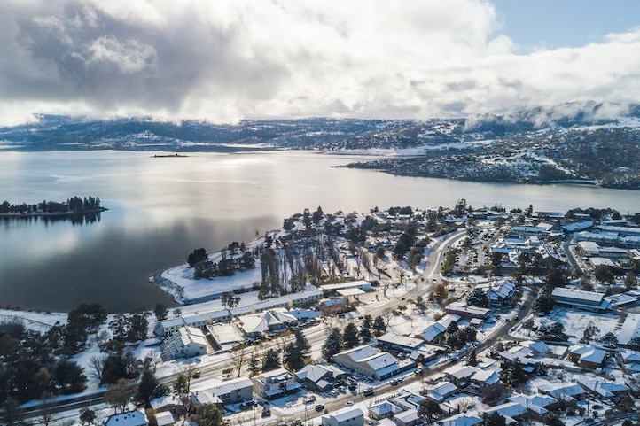 Aerial image of Jindabyne covered in snow, beside the Lake.