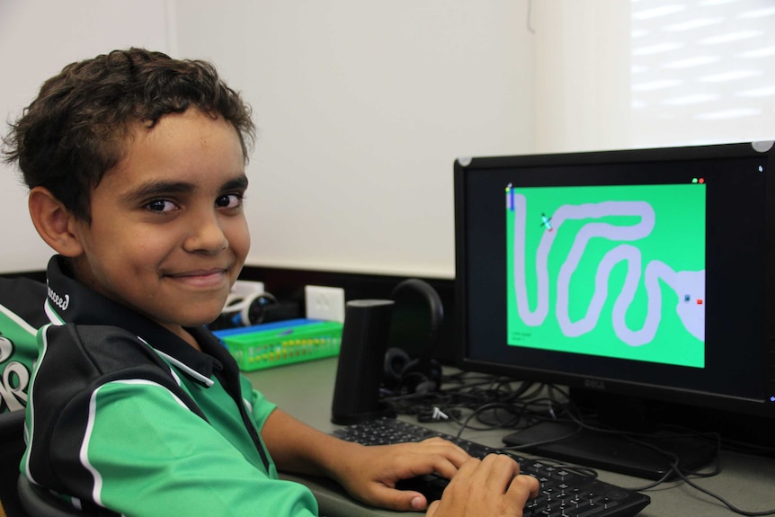 Primary school student River, working on his computer game, smiling.