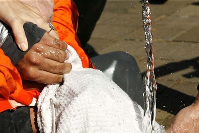 A demonstrator is held down during a simulation of waterboarding