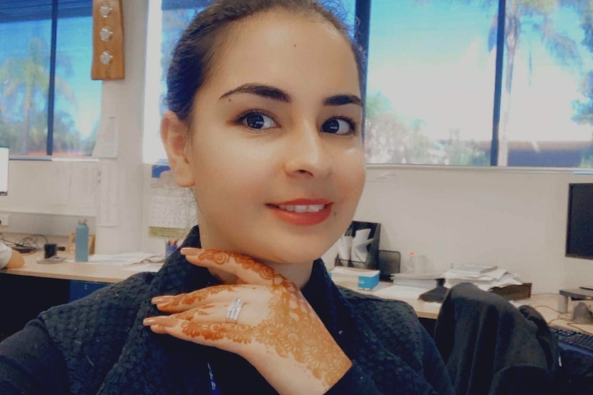 Husna Nabi holds up a hand covered in a henna tattoo pattern.