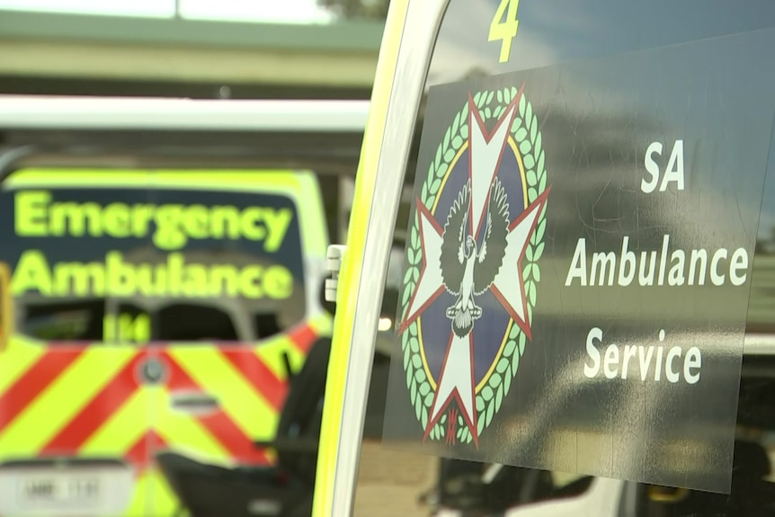 An SA Ambulance Service sign on the side of a vehicle with another in the background saying Emergency Ambulance